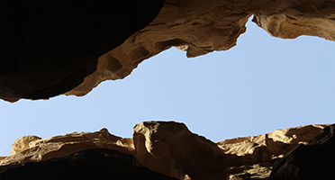 Looking up at the sky from inside a canyon with brown mountains and a blue sky