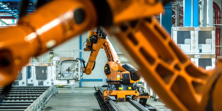 Photo of two robotic arms doing work in a factory assembly line